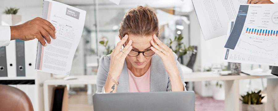 Stressed employee overwhelmed by paperwork and data, illustrating the challenges of legacy AP processes.