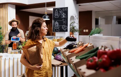 A woman holding a bag and picking vegetables