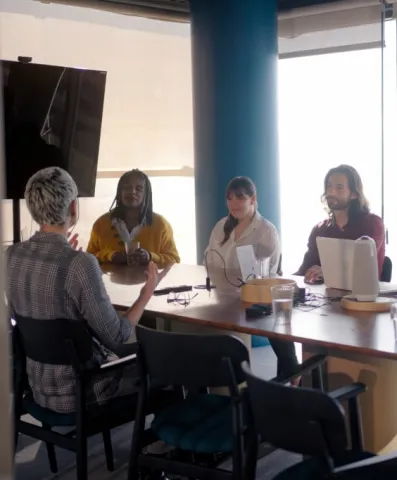 A group of people sitting in front of a table in a meeting