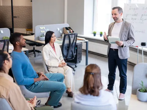 a person standing in front of a group of people during pre-workshop preparation session