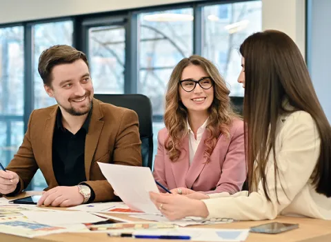 Absoft employees in a modern Absoft office setting discuss documents and charts, symbolizing the company’s deep expertise and collaborative approach to SAP payroll solutions.